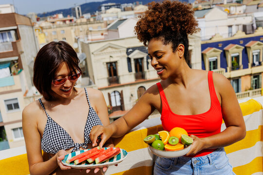 Friends sharing fresh fruit on a sunny rooftop