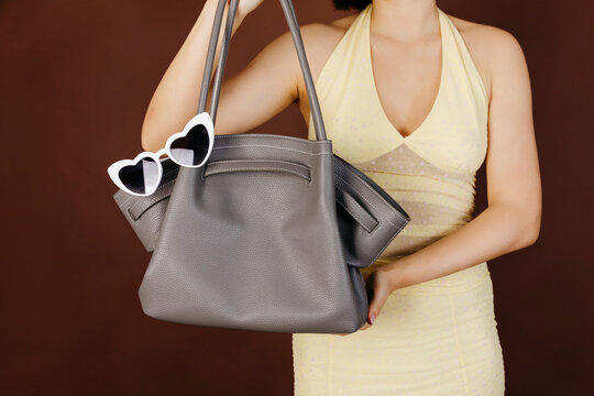 Woman holding gray leather bag 