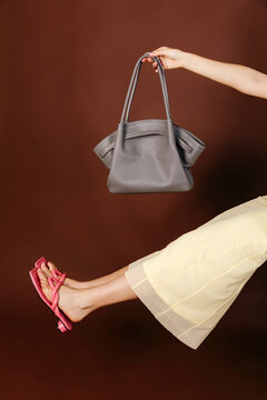 Woman holding grey handbag with pink sandals