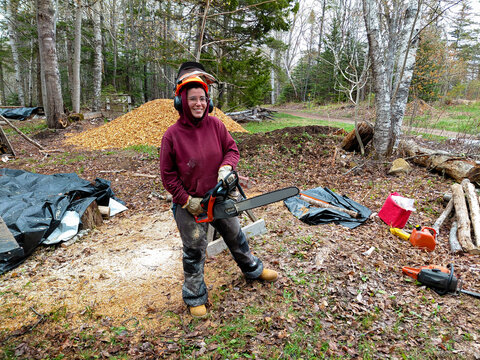 Cheerful woman with a chainsaw doing wood work