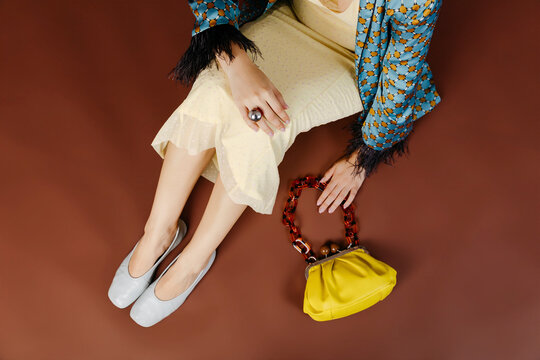 Woman on floor wearing fashion clothing and yellow handbag