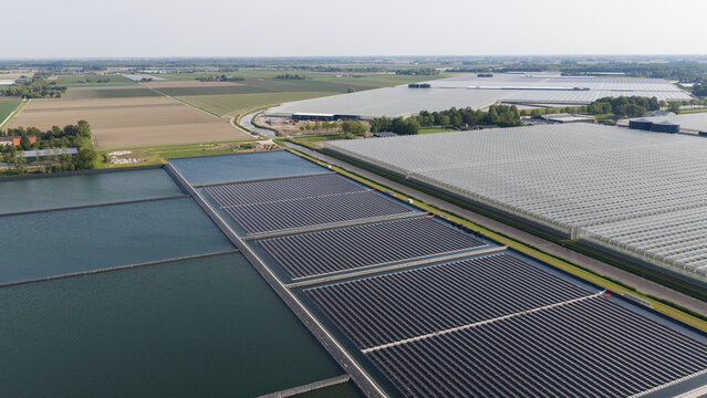 Aerial View of Floating Solar Panels Powering Industrial Greenhouses