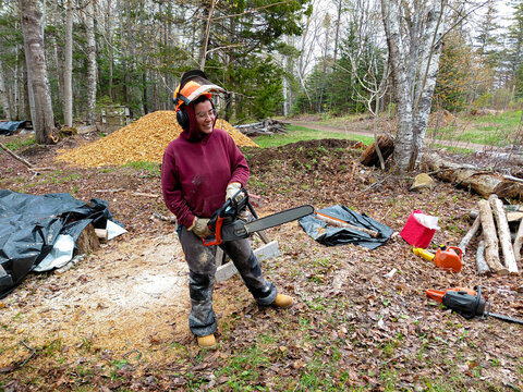 Cheerful woman with a chainsaw doing wood work