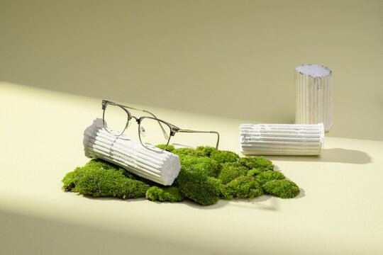 Artistic composition featuring eyeglasses resting on lush green moss
