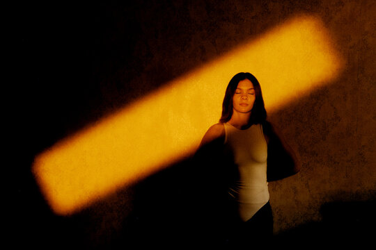 Woman with eyes closed under dramatic light beam