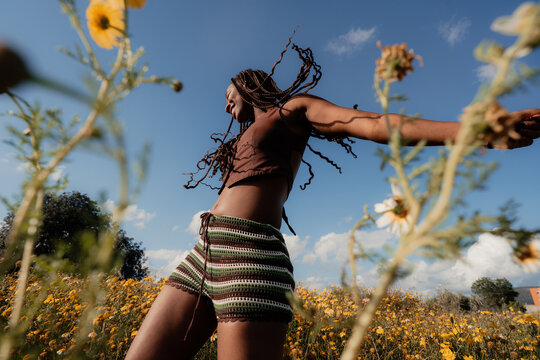 Woman Dancing in a Field of Flowers Under a Bright Sky