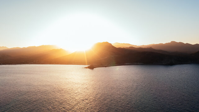 golden sunset over calm bay with mountain island silhouette
