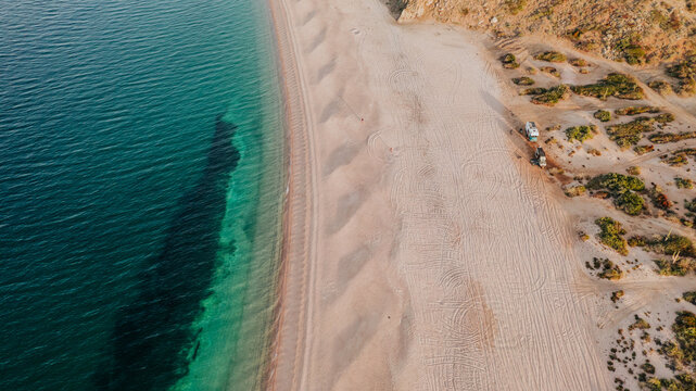 aerial view of camper on pristine white sand beach with turquois