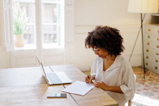 Smiling businesswoman writing notes at office desk