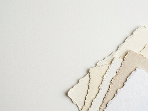 Torn paper sheets in various shades scattered on a surface