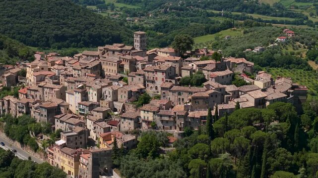 Casperia medieval borgo tight zoom drone flight over authentic hilltop town Italy. Cinematic 70mm aerial telephoto orbit of compact historic stone houses among green hills and trees. Lazio 4K.