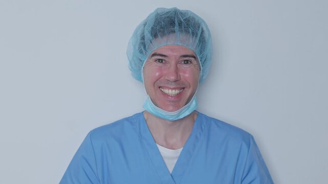 Smiling male doctor removing surgical face mask