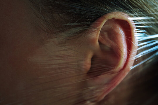 Woman's ear wrapped in transparent plastic foil