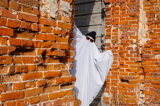 Ghostly figure in Halloween costume by brick wall