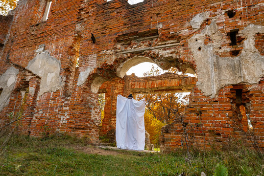 Ghost in sheet at ancient brick ruins during autumn