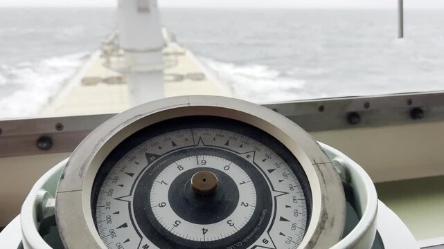 compass at vessel cockpit, navigation bridge. ship proceeding at ocean and steering course.