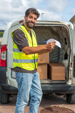 vertical Delivery driver holding clipboard near van with packages