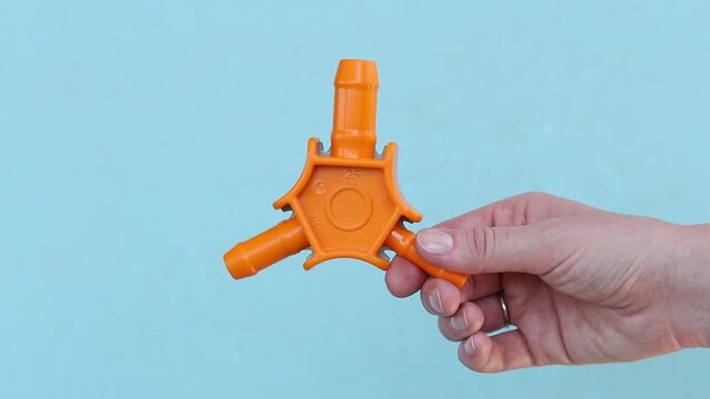 Close-up of a female hand with a plumbing tool for calibrating plastic pipes. Manual calibrator for metal-plastic pipes (16-20-25 mm) with beveling knives. Orange plastic calibrator