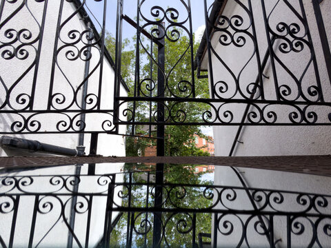 wrought iron fence with mirror reflection and trees in the background 