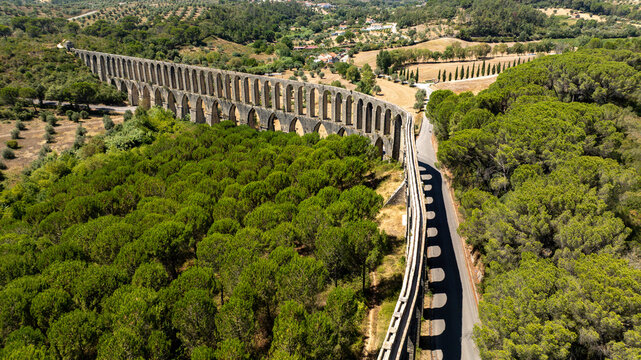 Aerial view of the historic Aqueduto do Convento de Cristo - Troco Pegoes Altos, a stone arch structure crossing pine forests and rolling hills in Tomar, Santarem, Portugal.