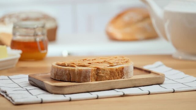 Peanut butter spread on fresh bread slice, homemade breakfast preparation, copy space
