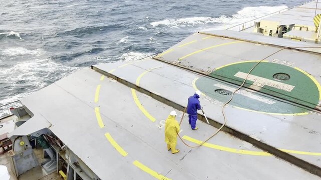 seafarer job when vessel underway at sea. washing the ship use fire hose and nozzles. ocean surface in view.