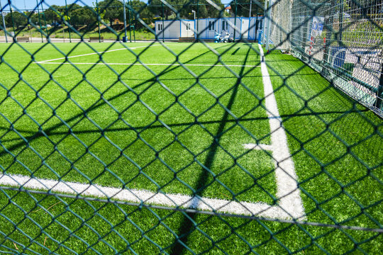 Green soccer field behind wire mesh fence on sunny day