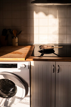 Sunlit kitchen stove with steaming pan and tiled wall