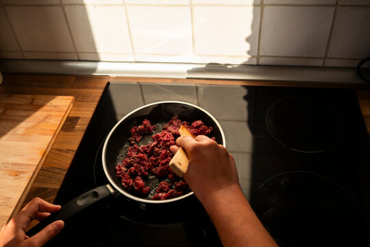 Cooking minced beef in frying pan on modern kitchen hob