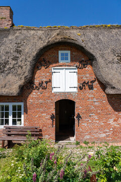 Thatched roof brick house with a wooden bench on Langene&szlig; island