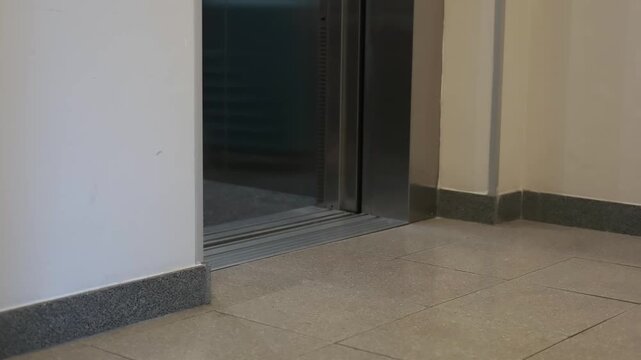 Female traveler with blue suitcase enters elevator, showcasing the transition from hallway to elevator interior in a modern building setting