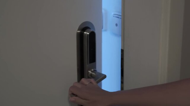 Hand inserting a key card into a modern electronic door lock, followed by the door opening to reveal a brightly lit interior space beyond the threshold