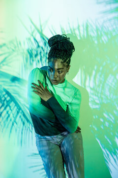 Afro woman dancer in green light with palm shadow