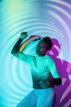 Afro woman dancer in neon light with abstract swirl backdrop