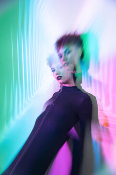 Cyberpunk young woman in neon blur futuristic corridor