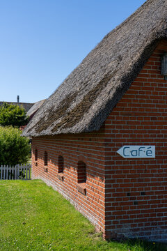 Caf&eacute; sign on a red brick building with thatched roof on Langene&szlig;