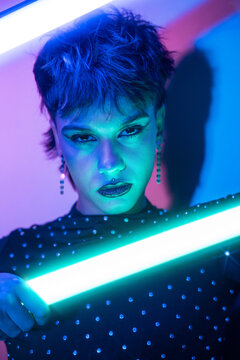 Cyberpunk young woman holding neon light in moody portrait