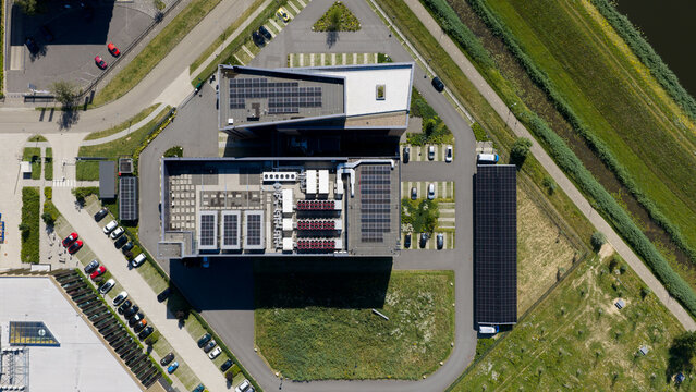 Aerial view of Interconnect Services BV facility featuring solar panels on rooftops, HVAC units, parking areas, and surrounding green space in 's-Hertogenbosch, Noord-Brabant, Netherlands.