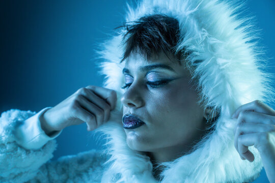Fashion model in white fur hood with icy blue lighting