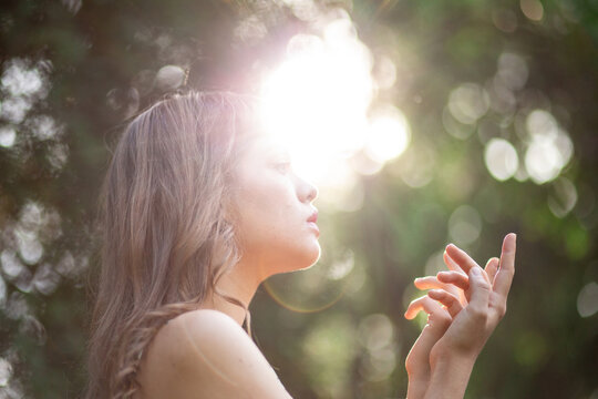 Serene young woman meditating outdoors in warm sunlight