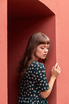 Young woman posing by red archway in floral dress