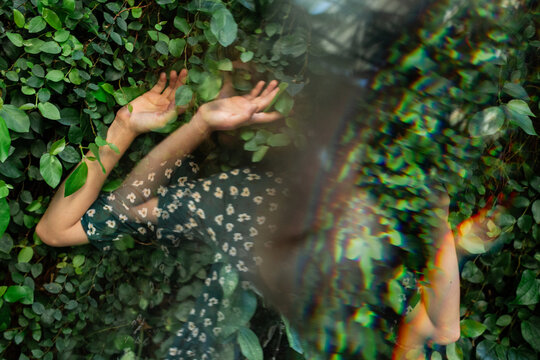 Anonymous abstract portrait with prism blur in green leaves