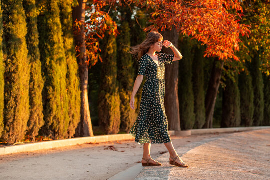 Woman walking at golden hour among autumn trees outdoors
