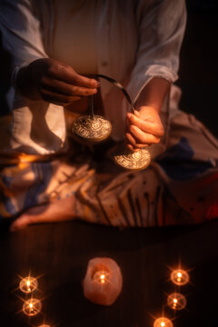 Latin woman performing esoteric ritual with cymbals and candle