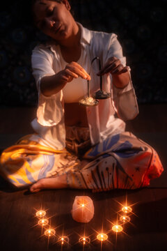 Latin woman performing esoteric candle ritual in darkness