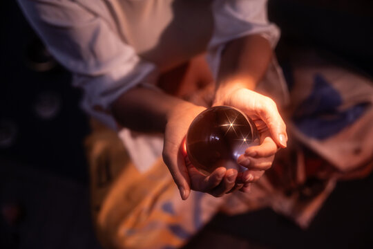 Latin woman holding crystal ball in esoteric ritual light