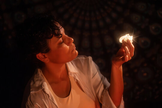 Latin woman holding crystal in candlelight meditation