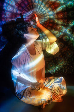 Latin woman holding crystal ball in esoteric aura light