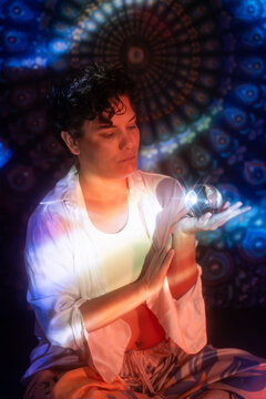 Spiritual Latin woman holding glowing orb in meditation