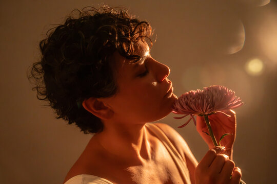 Spiritual Latin woman smelling a pink flower in soft light
